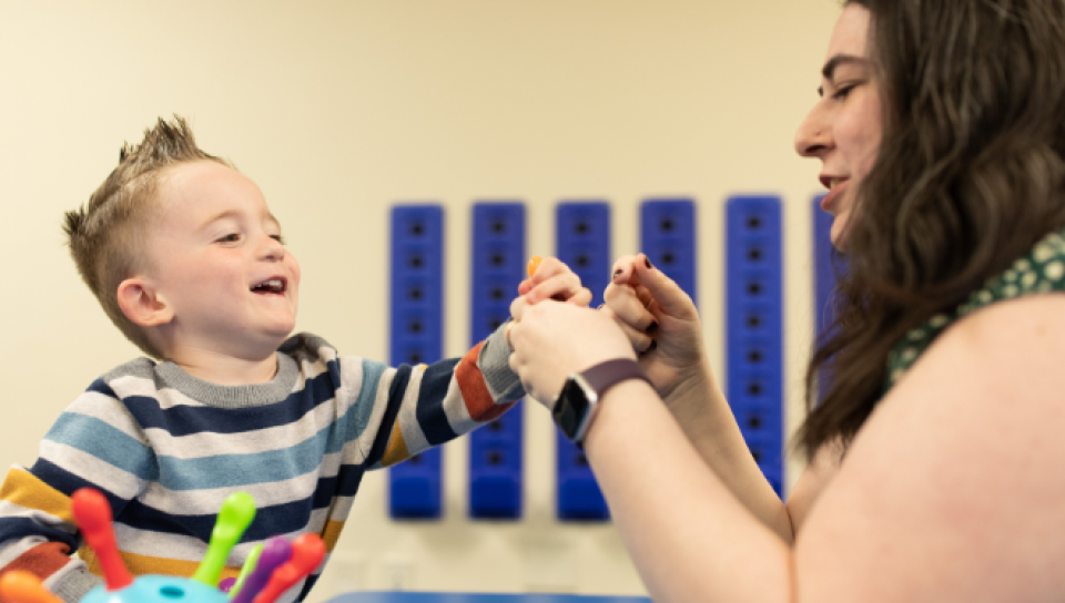 A young boy interacts with an early intervention specialist in a classroom.