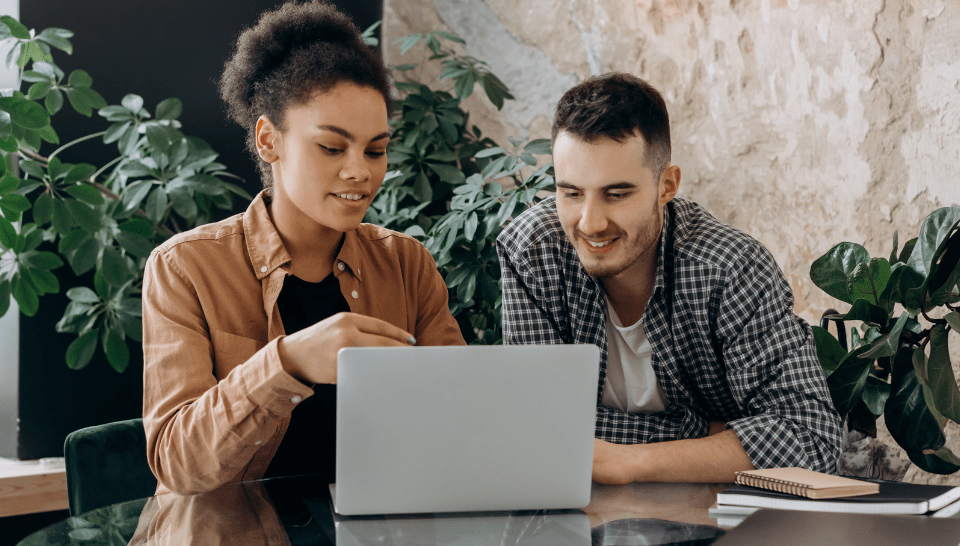 Two people are working together on a laptop.