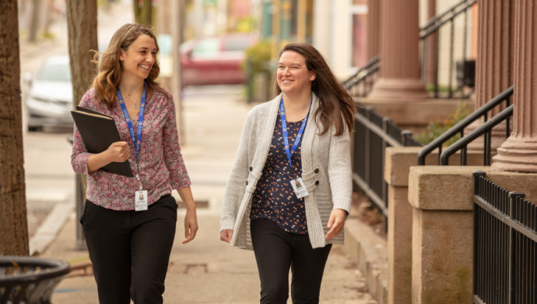 Two women who are early intervention professionals walk on a sidewalk in Providence.