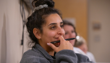 A student smiles while listening to Malcolm Streitfeld speaking to her class.