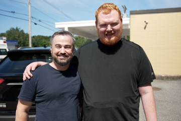 Two men smile at the camera.