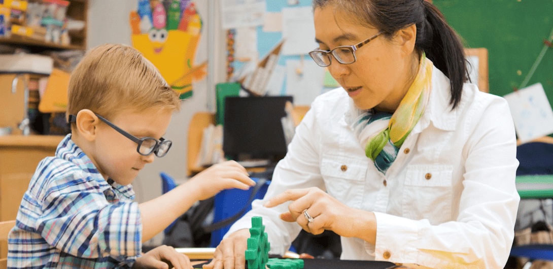 A teacher works with a visually impaired young boy.