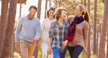 A family with young adult children walk in the woods.