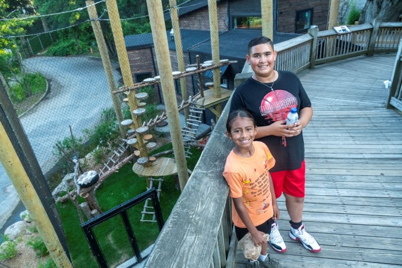 Two children pose near an animal exhibit.