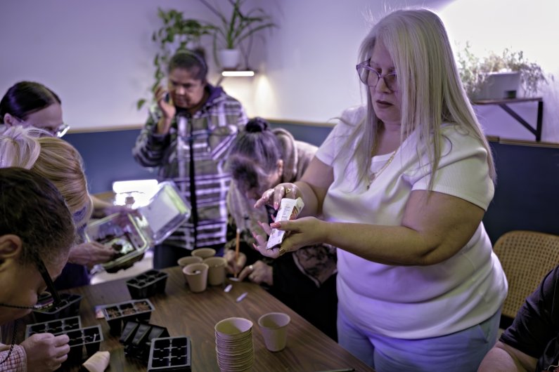 A woman reaches into a seed packet.