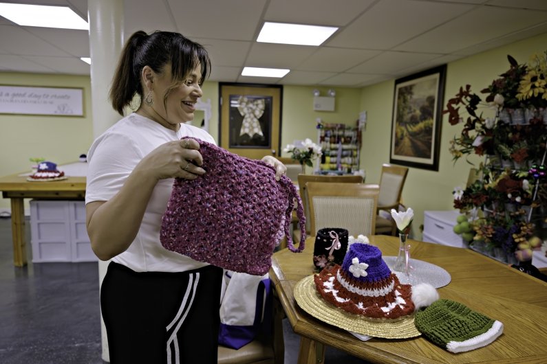 Valerie Gonzalez shows some of the knitted items the center participants have  created.