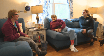 Three people sit in a living room.