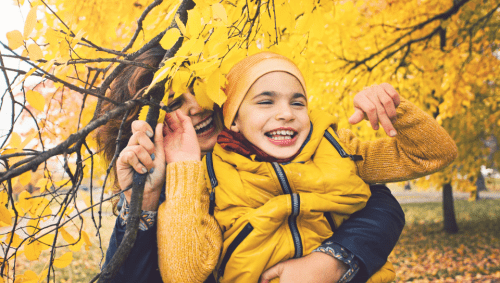 A mother and child in colorful fall leaves.