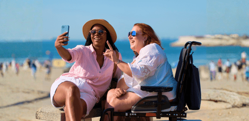 Two women take a selfie at the beach.