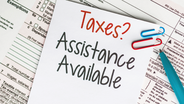 IRS tax forms are pictured with a note on top that reads: Taxes? Assistance Available.